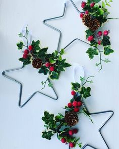 two star shaped christmas decorations with holly and pine cones