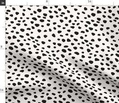 a white and black animal print fabric with lots of spots on the top of it