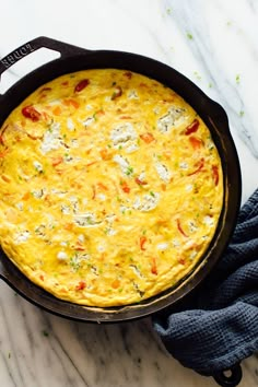 an omelet in a cast iron skillet on a marble counter with blue napkins