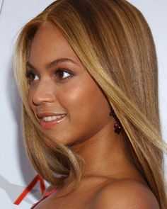 a close up of a person with long blonde hair and wearing a red strapless dress