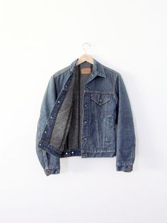 A 1970s vintage Levi's denim jacket with blanket lining. The dark wash Trucker jacket has a flannel lining. Ithas pockets on the chest, and hand warming pockets at the waist. It features the classic button backs, button cuffs, and button down closure. Style 70506 CONDITION In good condition with wear consistent with age and use.. There is a slight sun fade on the shoulders. SIZE & MEASUREMENTS Tag Size:                34 Approximate Fit: Small  Bust:                36"  /91.4 cm Length:                 24 inch  /      61 cm Shoulders:        17.5 inch  /      44.5 cm Neck to Sleeve End:                33 inch  /      83.8 cm For best fit, please compare measurements with a jacket of your own.  HOW WE MEASURE → Jacket measured lying flat.  → Bust measured armpit to armpit.  → Length measure Jean Jacket Outfits Men, Lined Jean Jacket, Vintage Levis Denim Jacket, Denim Jacket Vintage, Levi Denim Jacket, Png Clothes, Flannel Lined Jeans, Jean Jacket Outfits, Levis Denim Jacket