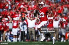 a football player running with the ball in his hand and people watching from the stands behind him