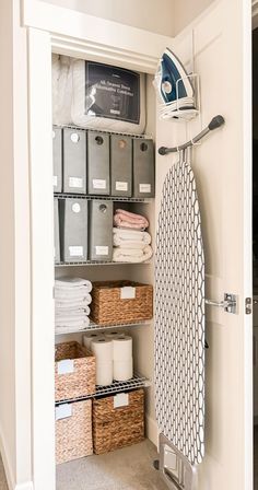 an ironing board and some baskets in a closet