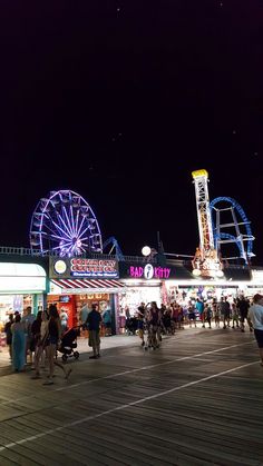 people are walking around an amusement park at night