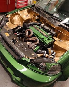 a green car with its hood open and the engine in it's center compartment