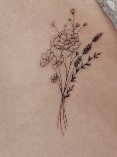 a woman's lower back tattoo with flowers and leaves on her left side ribcage