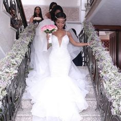 the bride is walking down the stairs with her bouquet