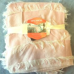 a pink blanket with fringes on it and an orange tag hanging from the end