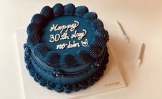 a blue birthday cake sitting on top of a white table next to a toothbrush