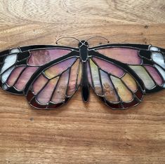 a stained glass butterfly sitting on top of a wooden table