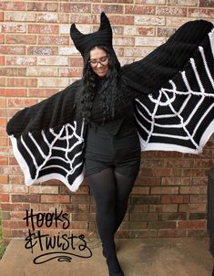 a woman wearing a black and white knitted bat costume with spider webs on it