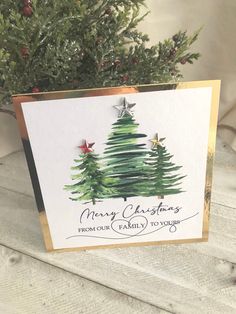 a christmas card with a pine tree and stars on the top, sitting next to a potted plant