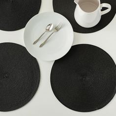 four place mats with silverware on them and a white coffee cup in the middle