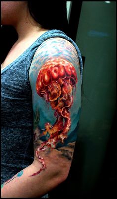 a woman's arm with an octopus and jellyfish tattoo on her left arm