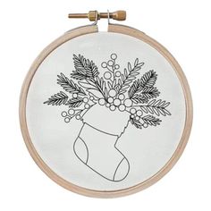 an embroidered christmas stocking with holly and berries on it is hanging from a wooden hoop