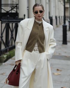 a woman is walking down the street with her handbag in her pocket and wearing white pants