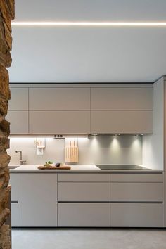 a modern kitchen with stone walls and white counter tops, built into the side of a cliff