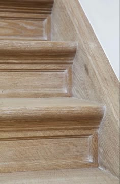 close up view of wooden stairs and handrails with white walls in the background