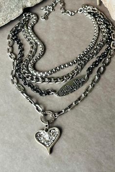 The ALL YOU NEED IS LOVE necklace is a unique  multilayer  piece  that features 4 different chains. There's a textured thick links box , chunky silver curb , gunmetal rolo and a mix links  chains .  Two focals are attached to different strands . An antique silver oblong tag embossed with "all you need is love"  is on the gunmetal rolo and a rustic heart that is hand paved is dangling on the longest layer which  is the mix links chain .  - Necklace is adjustable from 12" to 18".  - Silver chains are stainless steel and/or iron . -Gunmetal chain is iron - Components are stainless steel. - Pendants are silver pewter, heart is hand paved with clear crystals.  Follow me on Instagram: ꜱᴛᴇᴇʟ22_ᴊᴇᴡᴇʟʀʏ My designs are created by me and assembled by my own hands. I  make small batches of each piece Chunky Metal Necklace With Heart Pendant, Silver Multi-strand Layered Necklace With Chunky Chain, Chunky Chain Heart Metal Necklace, Silver Gothic Necklace With Heart Charm, Silver Layered Necklace, Silver Gothic Charm Necklace With Adjustable Chain, Chunky Silver Necklace, Cute Surprises, Silver Chains