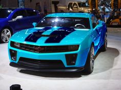 a blue sports car is on display at an auto show with other cars in the background