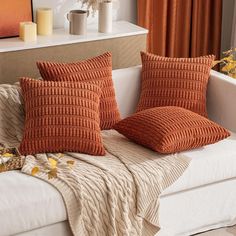 two orange pillows sitting on top of a white couch