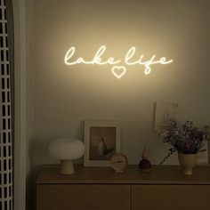 a neon sign that says lake life on the side of a wall above a dresser