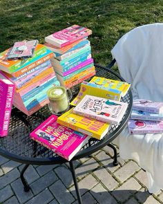 a stack of books sitting on top of a black table next to a chair and blanket