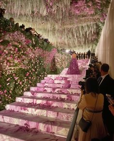 people are standing on the steps in front of pink flowers and icicles hanging from the ceiling