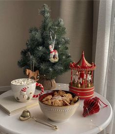 a bowl of cereal sitting on top of a white table next to a christmas tree