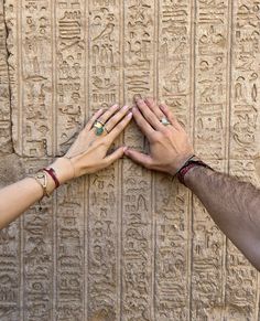 two hands touching each other in front of an egyptian wall