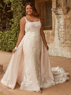 a woman in a wedding dress posing for the camera with her hand on her hip