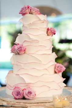 a three tiered wedding cake with pink roses on top