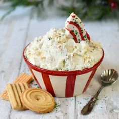 a red and white bowl filled with food next to crackers on top of a table