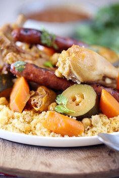 a white plate topped with meat and veggies on top of couscous