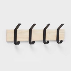 three black hooks hang from the wall on a coat rack with four wooden pegs