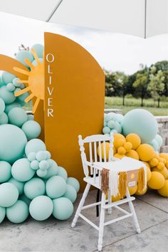 a white chair sitting in front of a giant balloon arch with yellow and blue balloons