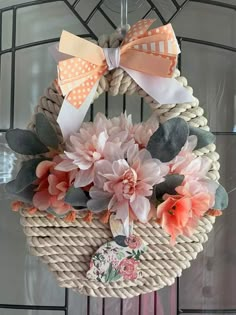 a wreath with flowers and bows hanging from it's side on a door hanger