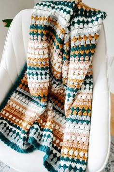 a crocheted blanket sitting on top of a white chair