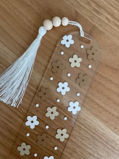 a clear case with white flowers and tassels on the top is sitting on a wooden table