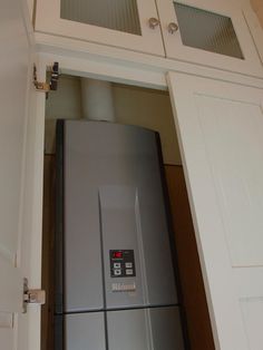 a silver refrigerator freezer sitting inside of a white kitchen cabinet next to an open door