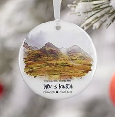 a personalized ornament hanging from a christmas tree with mountains in the background