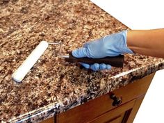 a person with blue gloves is cleaning a granite counter top