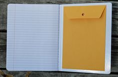 an open notebook with yellow paper attached to the front and back cover, sitting on a wooden surface