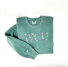 This Personalized College Sweatshirt, Embroidered with University School Colors makes a perfect  Graduation Gift for Girls.  Featuring Woodland Embroidery with Custom Colors determined by the particular school colors.  A name can also be added to the sleeve for even further personalization. SIZING INFORMATION ✨These are a relaxed fit.  Utilize the included size chart to determine your size. SWEATSHIRT PARTICULARS ✨Stitched on a perfect-for-embroidery Comfort Colors 9.5-oz Crew Sweatshirt.  It's soft and cozy while feeling substantial. ✨80% ring spun US cotton / 20% polyester ✨Relaxed fit, side seamed body HOW TO ORDER ✨Select Sweatshirt Size and Color from first drop-down menu ✨Select Embroidery Preference from second drop-down menu ✨Utilize personalization box to communicate school letter Cheap Custom Embroidery Varsity Top, Casual Green Sweatshirt With Embroidery, Green Long Sleeve Sweatshirt With Machine Embroidery, High School Sweatshirts, Woodland Embroidery, School Sweatshirts, West Chester Pa, University Shirt, University School