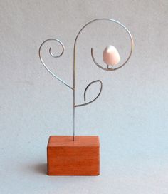 a small wooden stand with a white ball on it's end and a metal wire sculpture in the shape of a heart