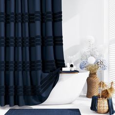 a bathroom with a blue shower curtain next to a white bathtub and rug on the floor