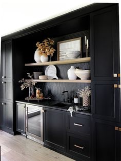 a kitchen with black cabinets and white vases