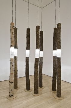 three tall wooden poles with lights hanging from them in a room filled with wood flooring