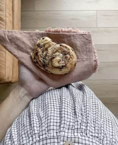 a person holding up a piece of food on top of a cloth covered object in their hand