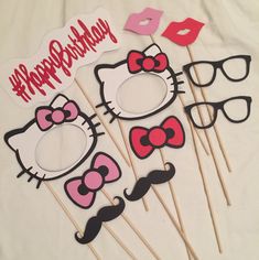 hello kitty photo booth props on a white sheet with pink and black bow tie, sunglasses and lips